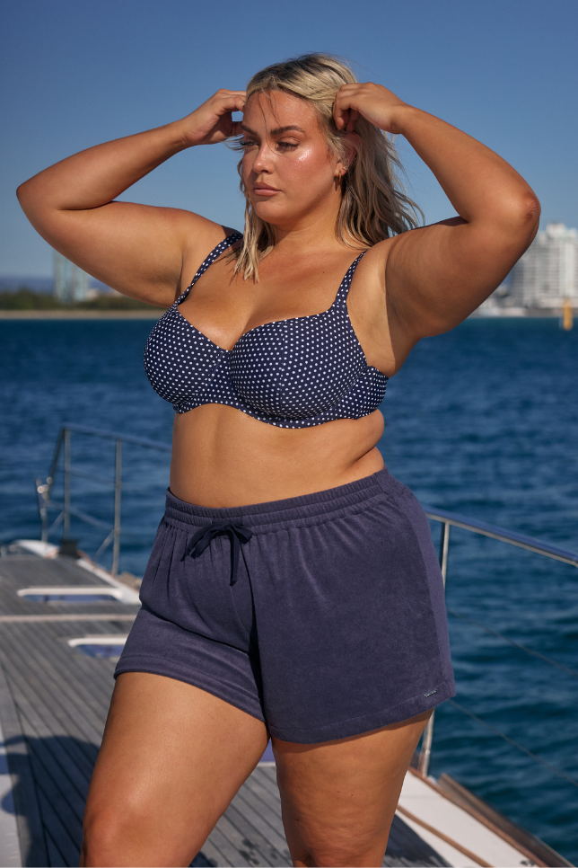 Model wearing navy shorts with navy dots bikini top