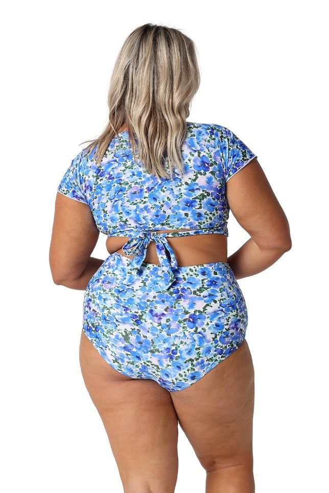 Model showing tie back of blue floral wrap crop top