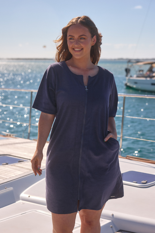 Model wearing navy zip up beach dress on boat