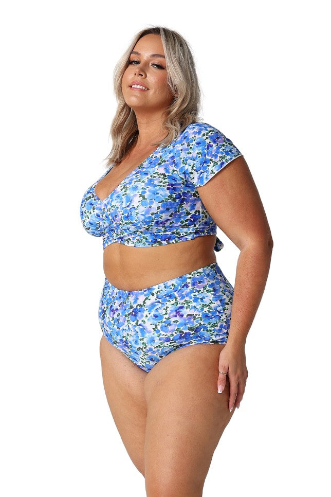 Model showing side of blue floral wrap crop top and matching pant