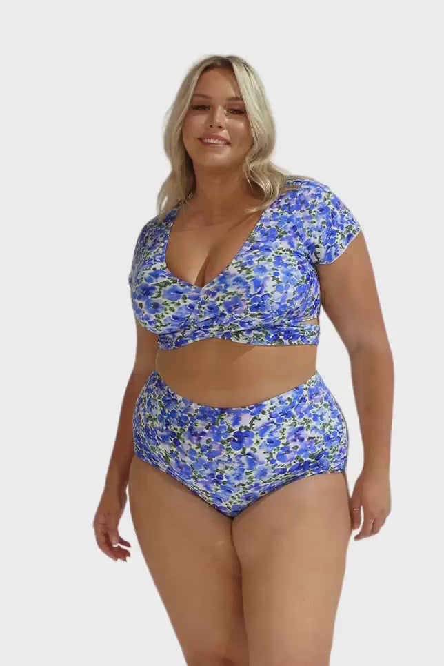 Model wearing blue floral wrap crop top and matching high waisted bottoms