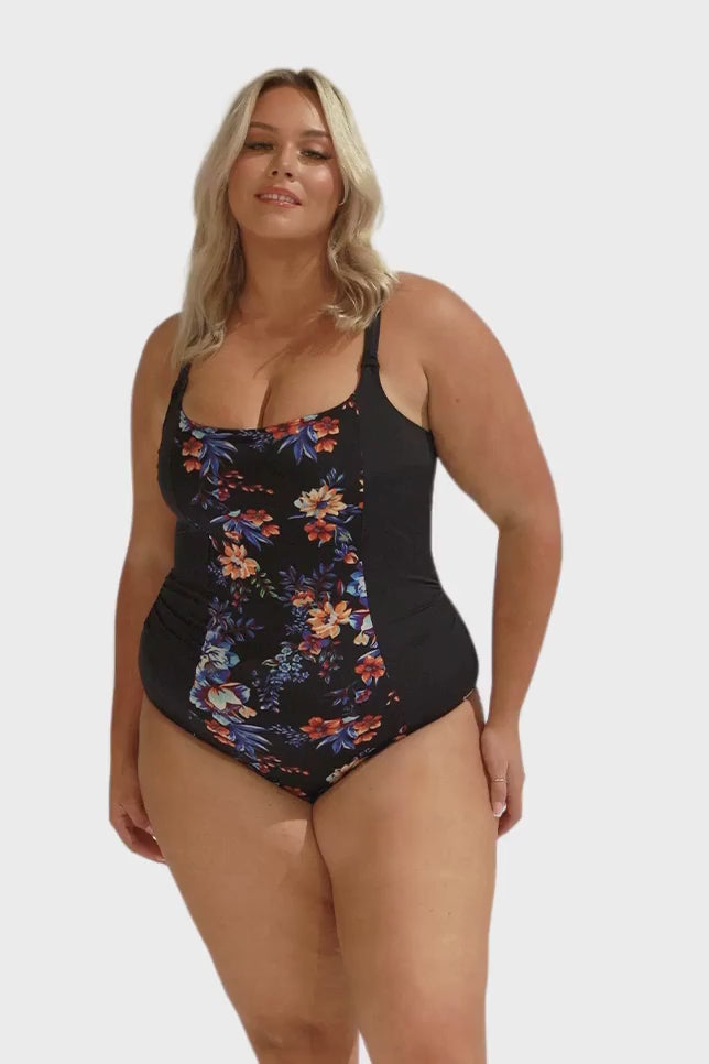 Model wearing black, blue and orange floral one piece swimsuit