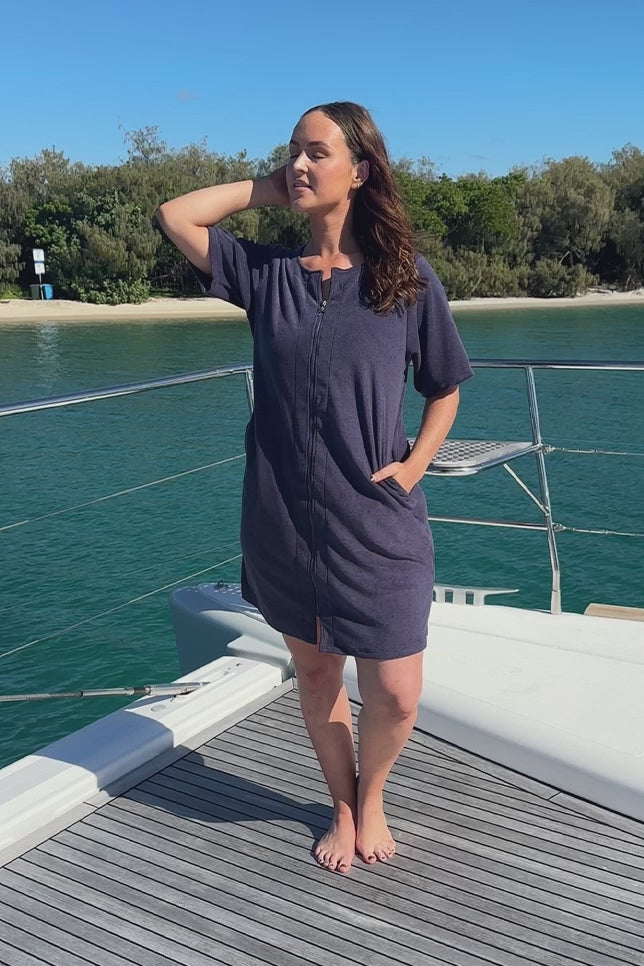 Model wearing navy zip through dress on boat