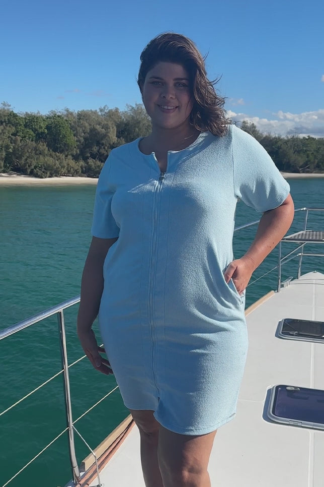 Model wearing light blue zip through cover up dress on boat